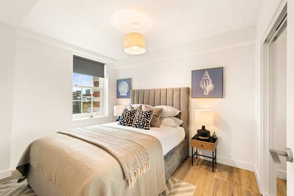 A bedroom with a large bed and a small table with a lamp.