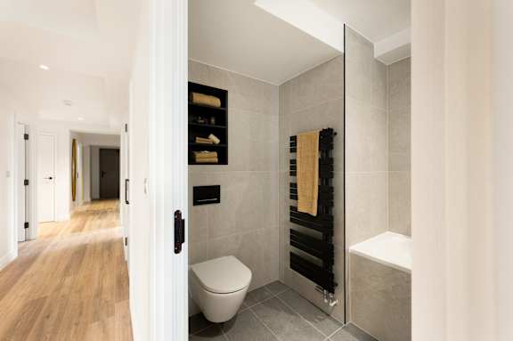 A bathroom with a toilet, a towel rack, and a bathtub.