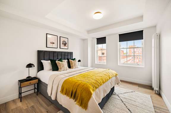 A bedroom with a bed, nightstand, and window.