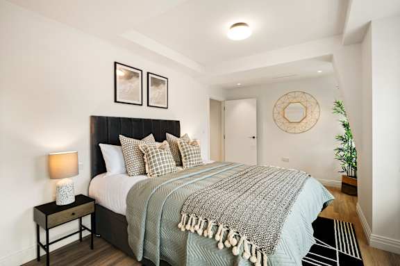 A bedroom with a large bed and a wooden nightstand.
