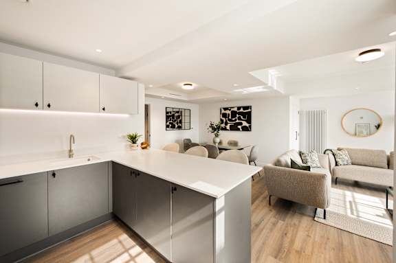 A modern kitchen with a white countertop and grey cabinets.