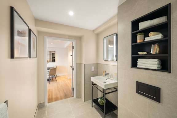 A bathroom with a sink, mirror, and towel rack.