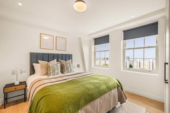 A bedroom with a large bed and a window overlooking a cityscape.