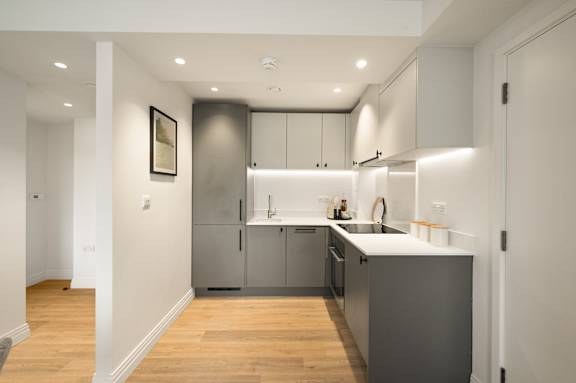 A modern kitchen with a wooden floor and stainless steel appliances.