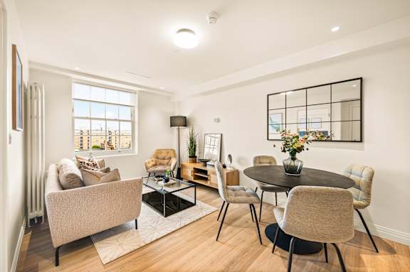 A living room with a brown sofa, a black coffee table, and a large window.