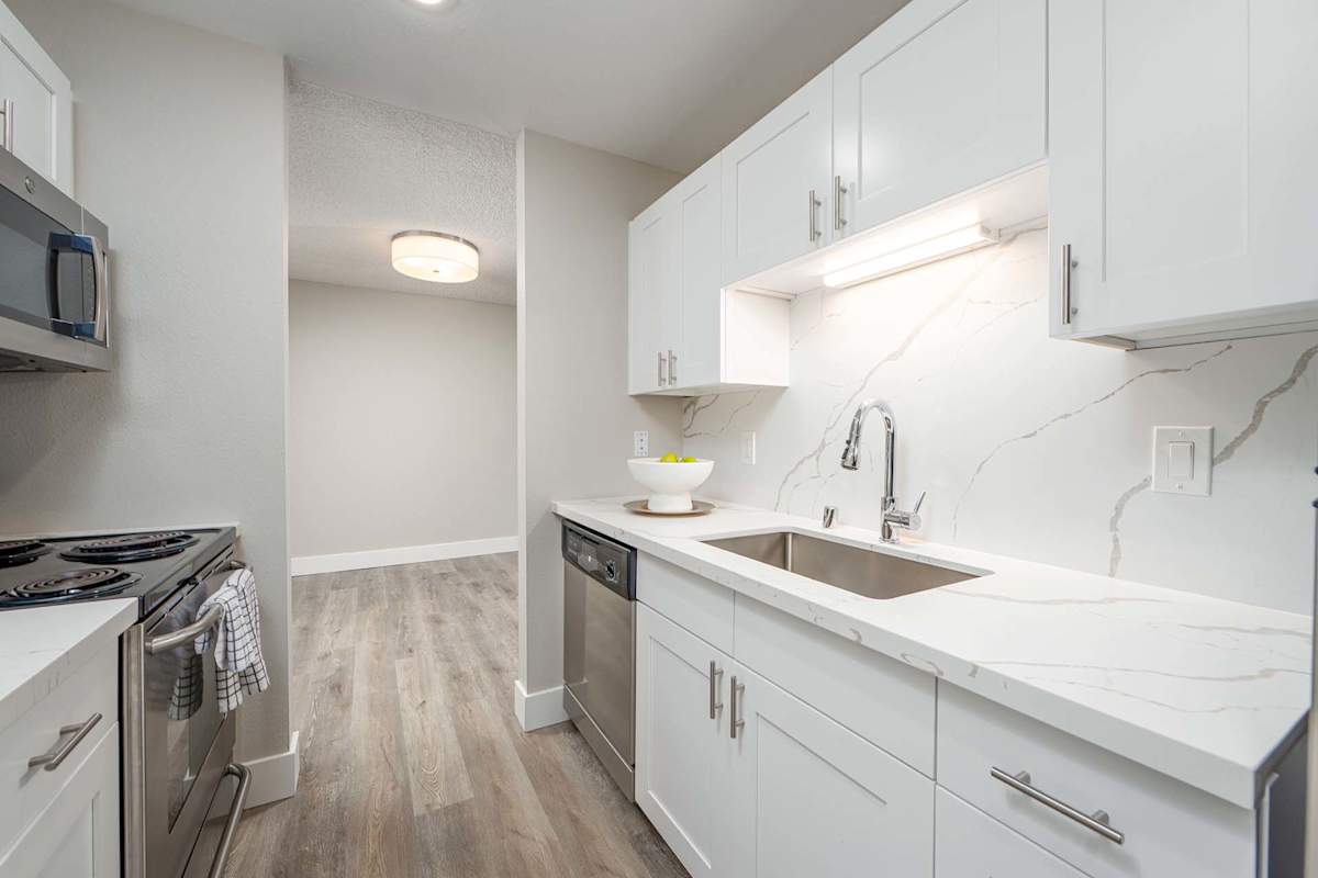 The Regent at Bellevue Way Apartments kitchen with stainless appliances and wood plank flooring - Bellevue, WA