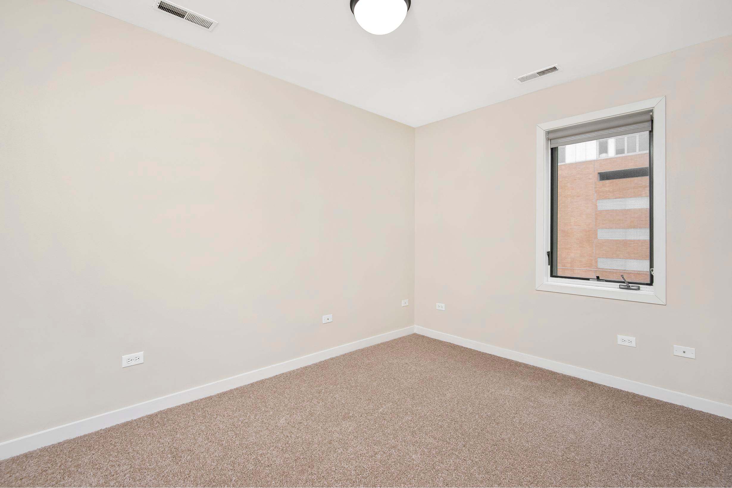 Oak Park Place apartment room with window and carpeted floor - Oak Park, IL