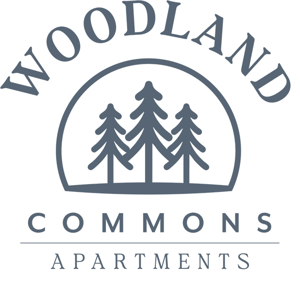 The image is a logo for Woodland Commons Apartments.