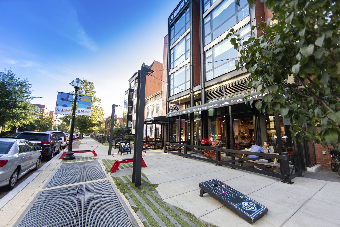 Street-level view of a Shaw corridor restaurant and outdoor seating on a sunny evening