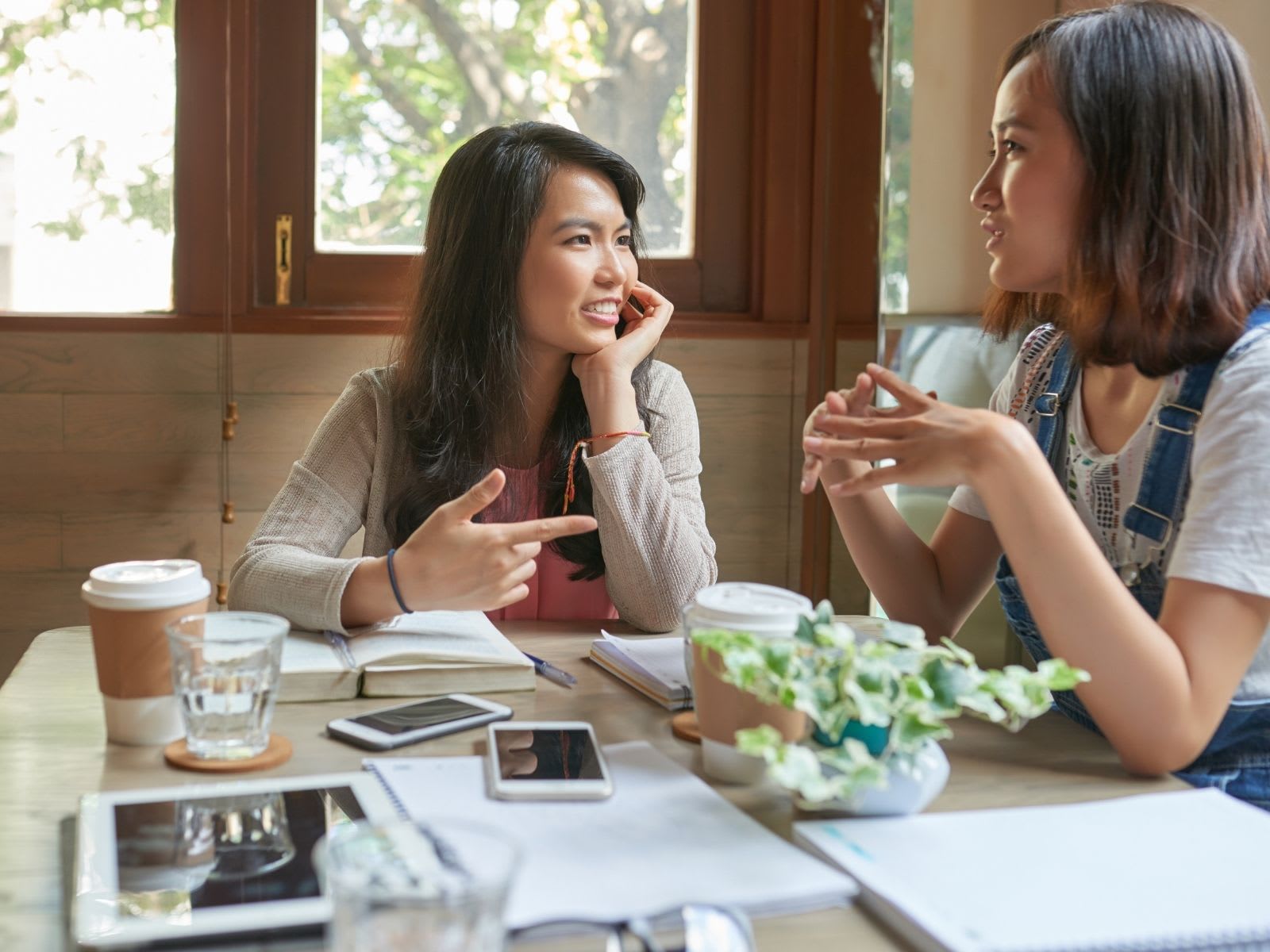 Two female students conversing inside a café