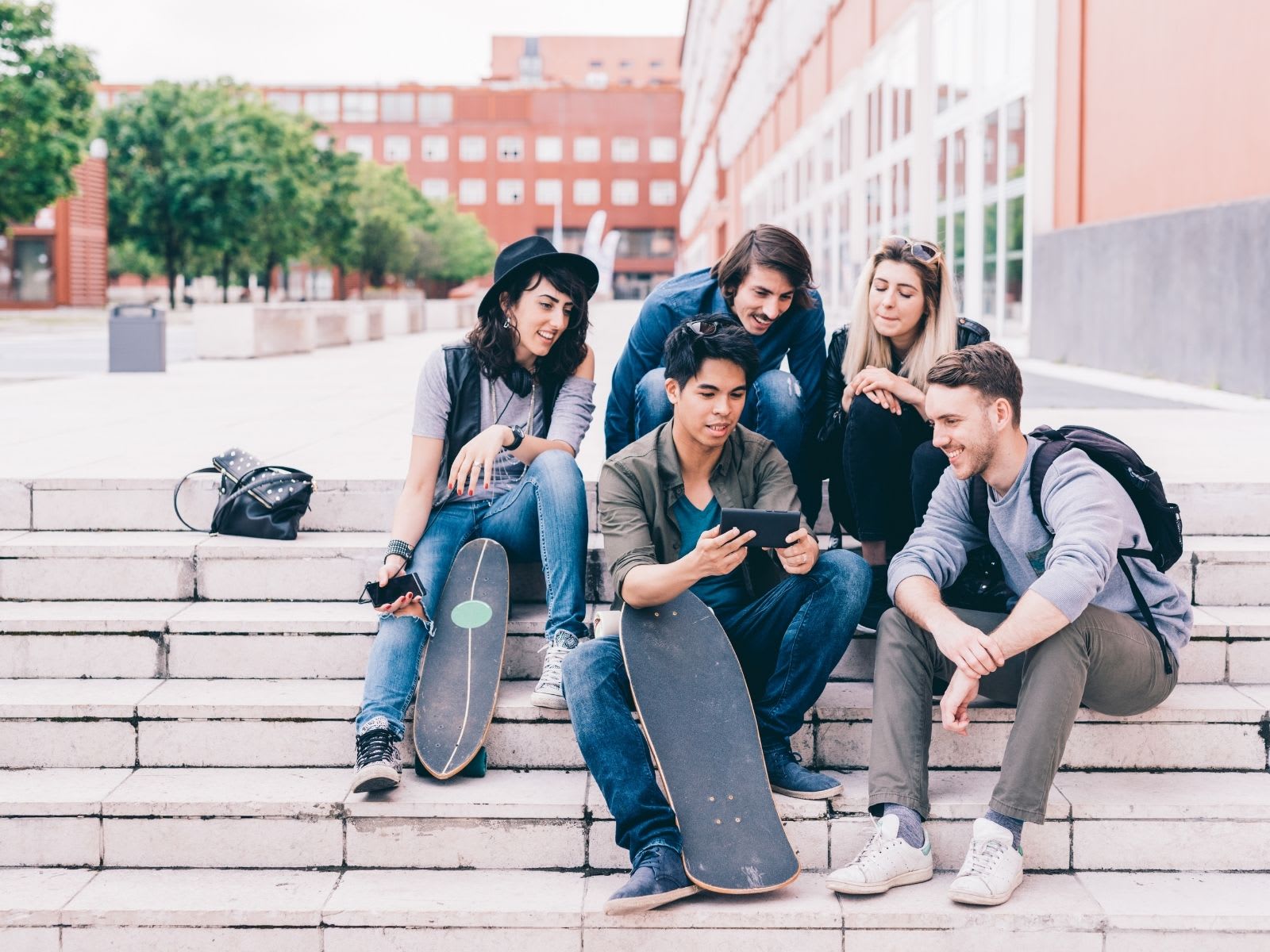 Group of students sitting together staring at friends phone
