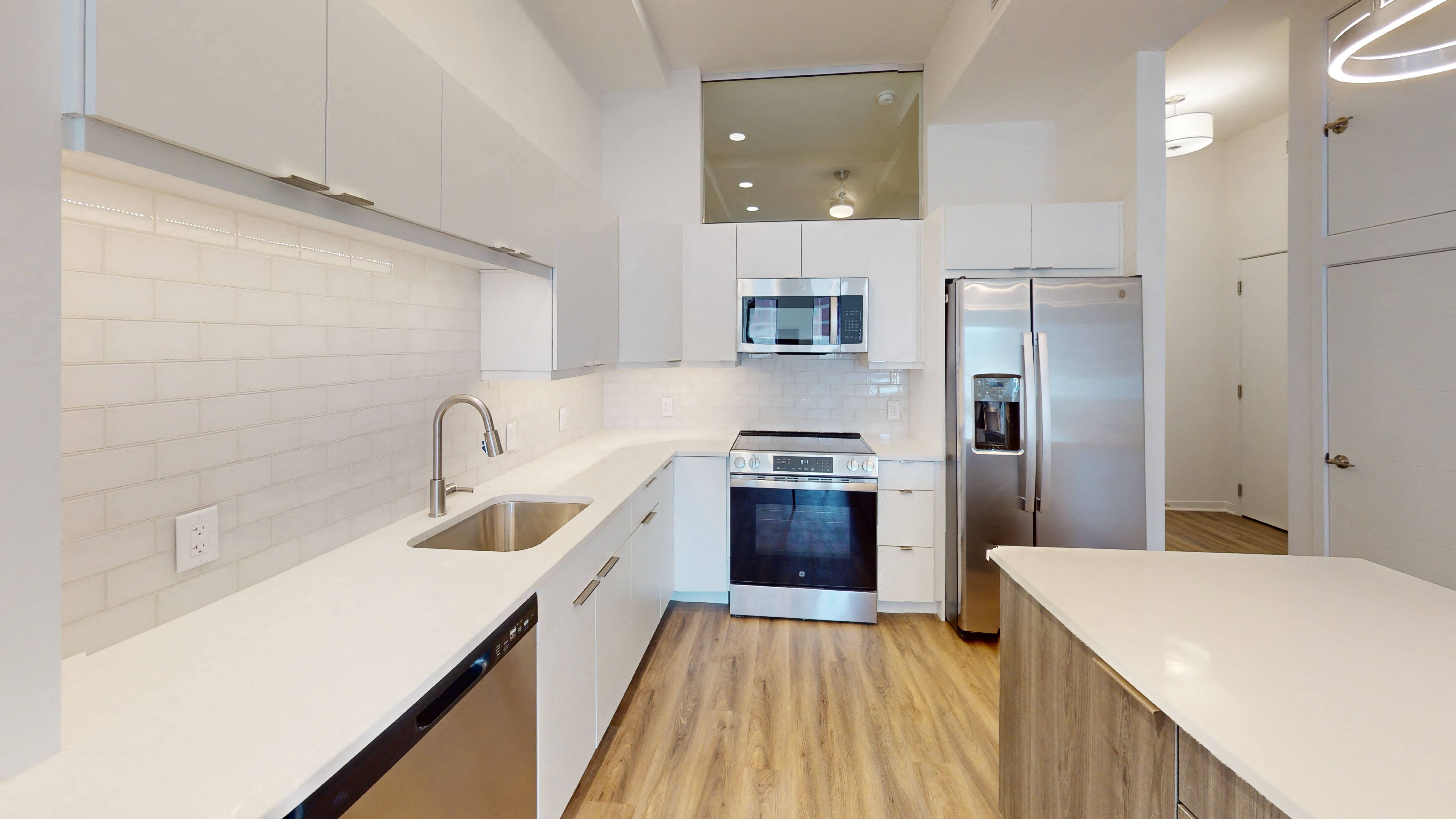 a kitchen with white walls and a wooden floor, Opens in new tab