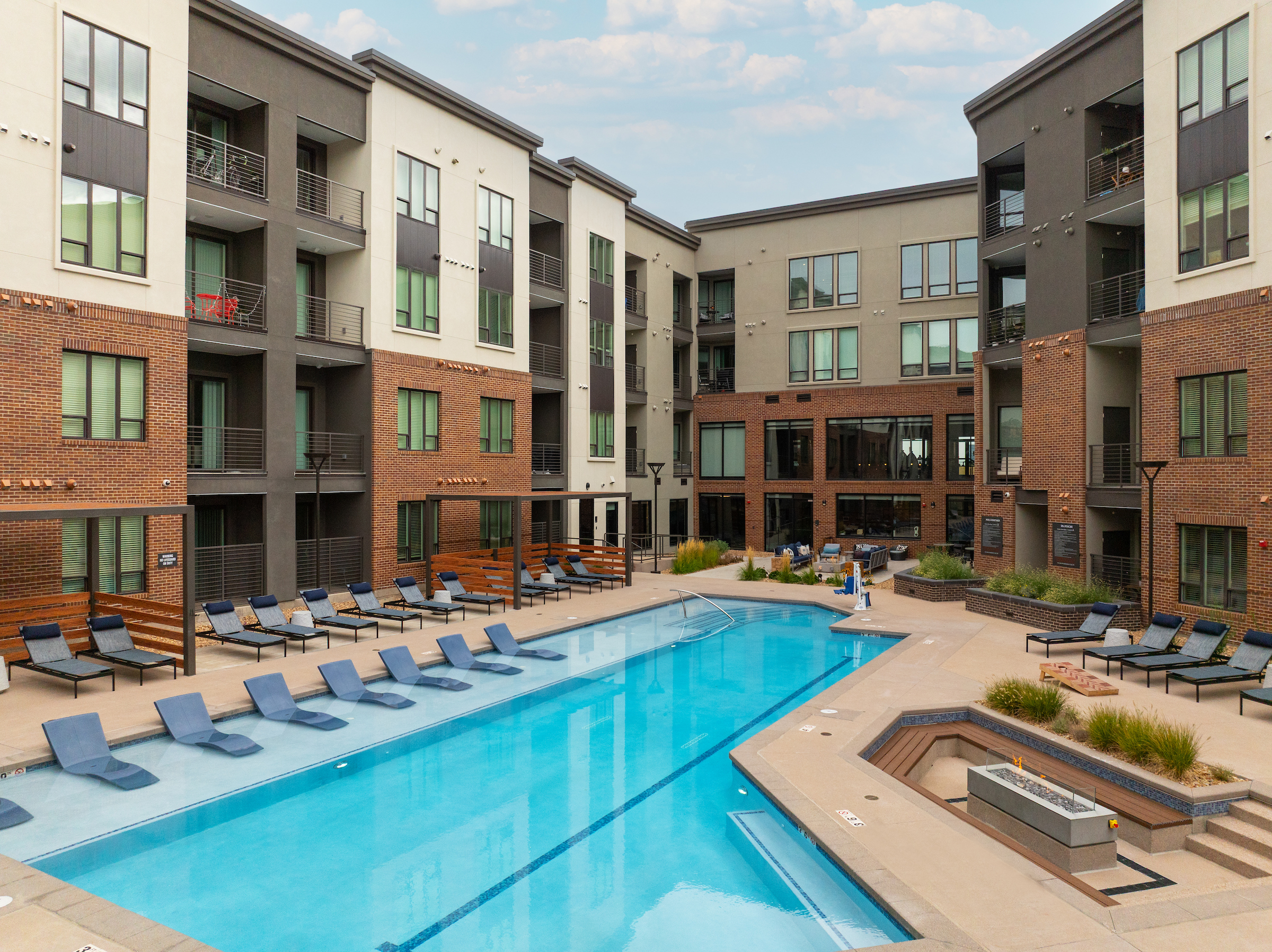 A swimming pool surrounded by lounge chairs and buildings.