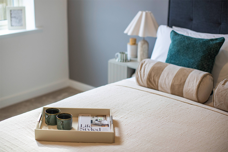 A tray with two cups and a magazine on a bed.