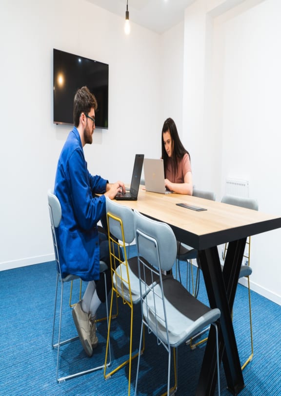 a man and a woman sitting at a table with laptops