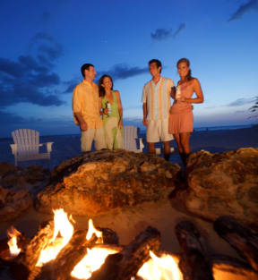 a family stands in front of a fire pit on the beach