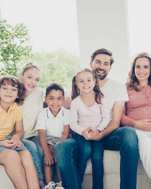 a family sitting on a couch and smiling at the camera at Creston Point, Seattle, Washington