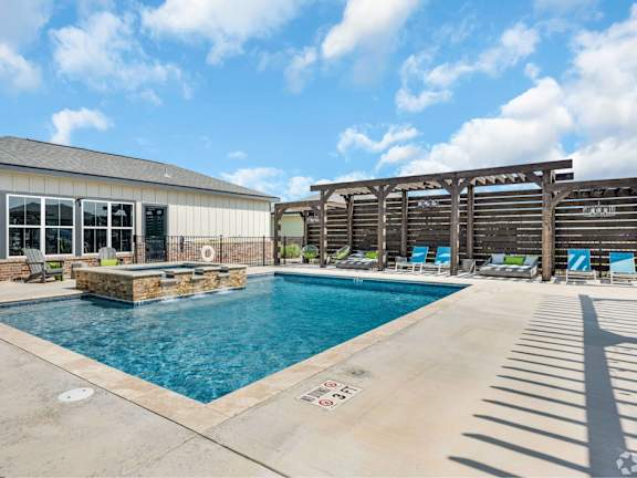 A pool with a water slide and a building behind it.