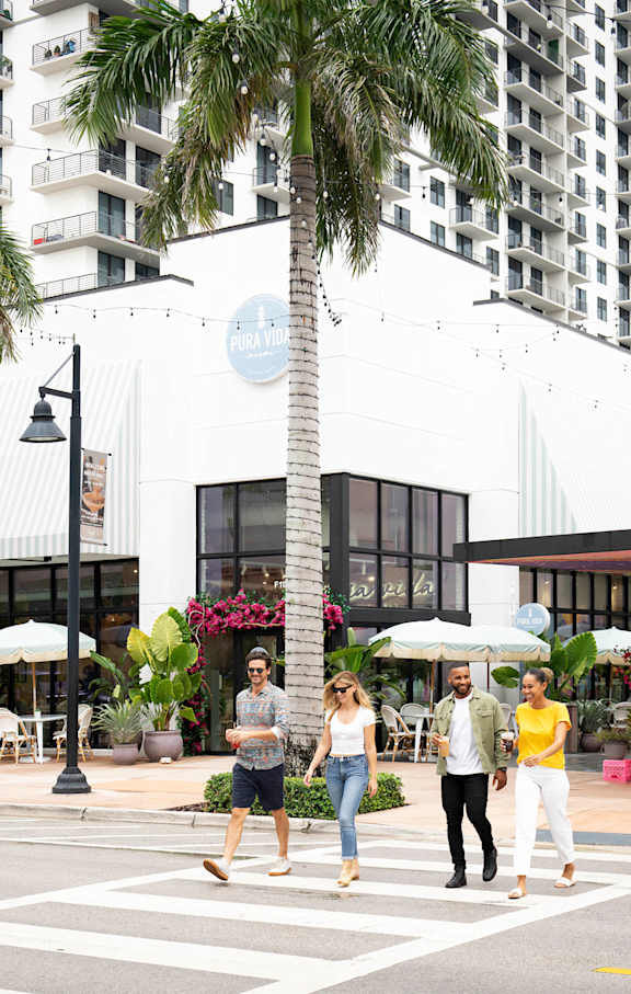 Four people are walking across a crosswalk. at Palma, Doral, FL