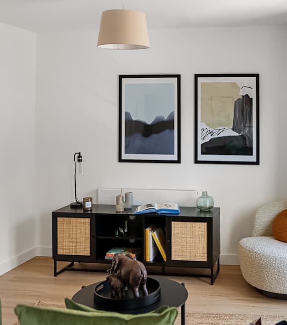 a living room with two pictures on the wall and a table with a stuffed animal