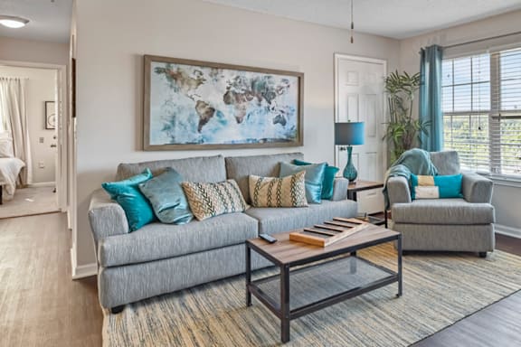 A living room with a grey couch and a large painting on the wall.