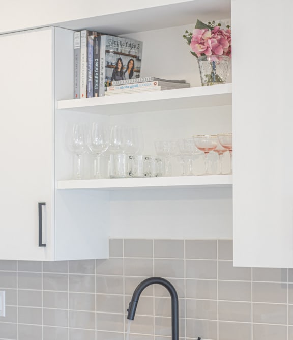a kitchen sink with a black faucet and white tiles