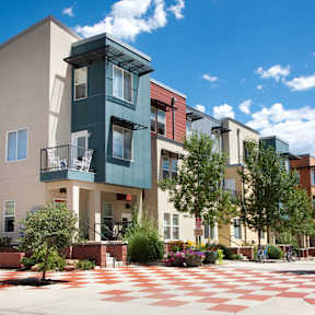 A modern building with a green and white facade is surrounded by a courtyard with a red and white checkered floor.