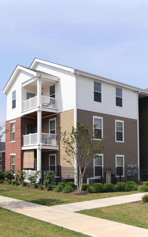 a white and brown apartment building with a sidewalk