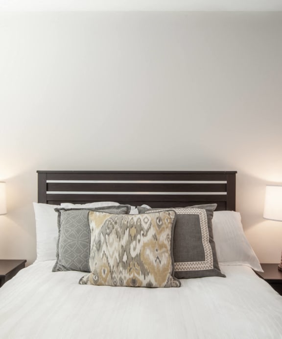 a bedroom with a bed with pillows and two lamps