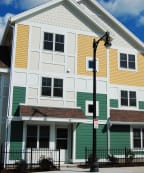 a white house with green and yellow siding and a street light