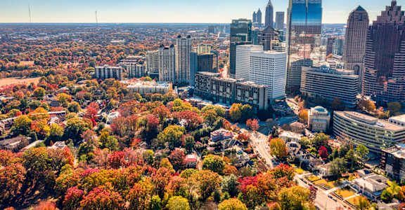 A cityscape with a mix of modern and older buildings, surrounded by greenery and roads.