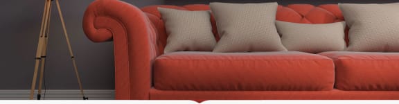 an orange couch with pillows and an umbrella in a room