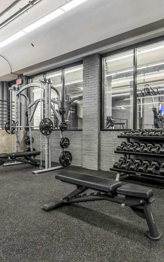 A gym with a bench, weights, and a mirror.