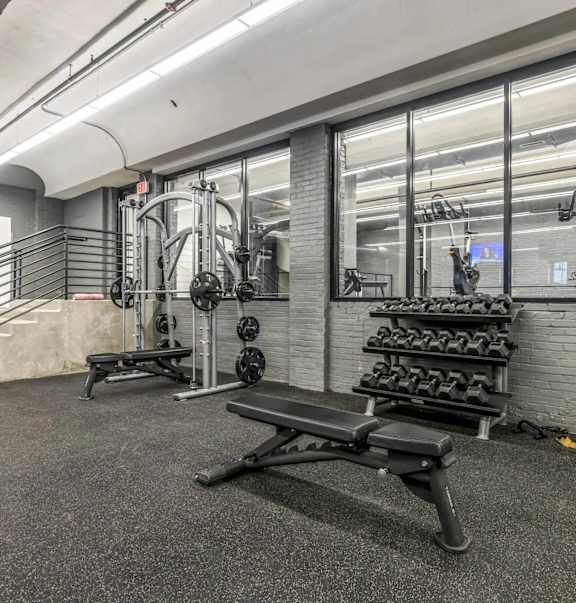 A gym with a bench, weights, and a mirror.
