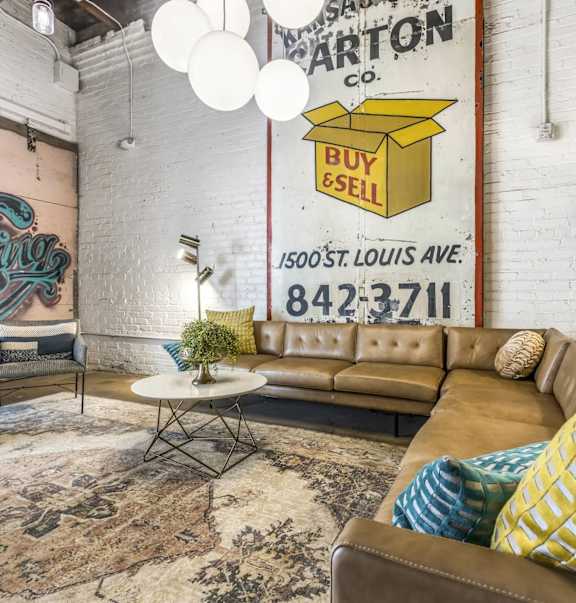 A living room with a brown leather couch and a white coffee table in front of a large poster.