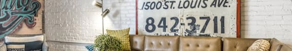 A living room with a brown leather couch and a white coffee table in front of a large poster.