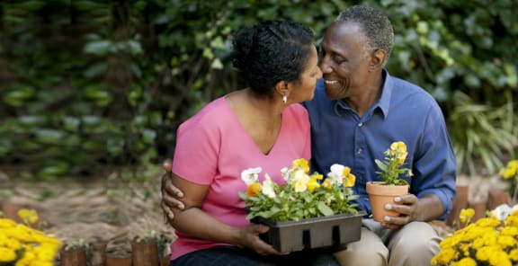 a man and a woman sitting next to each other holding a potted plant