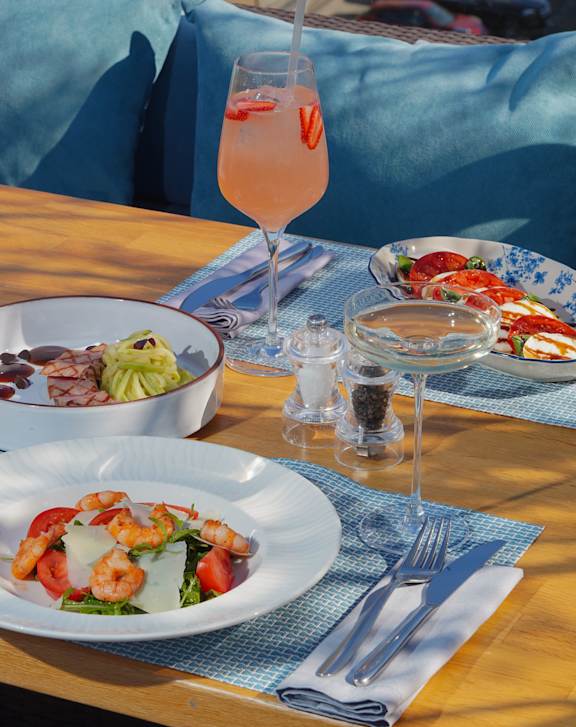 A table with a glass of drink and plates of food.