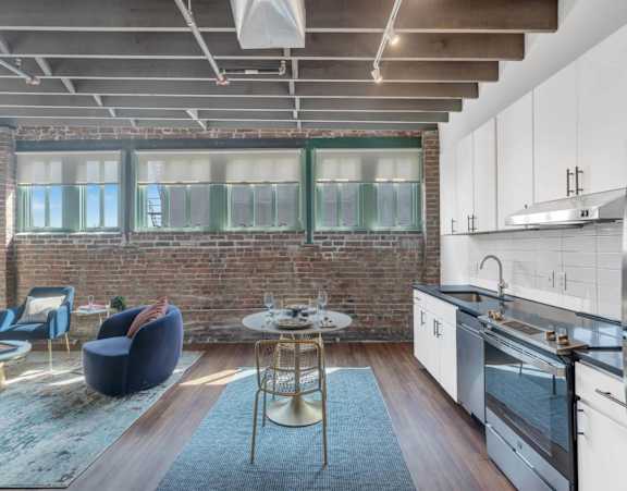 A modern kitchen with a brick wall and stainless steel appliances.