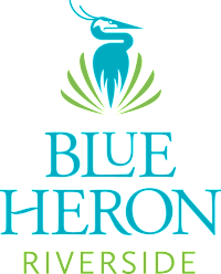 A logo with a bird and the words "Blue Heron Riverside" in front of it.