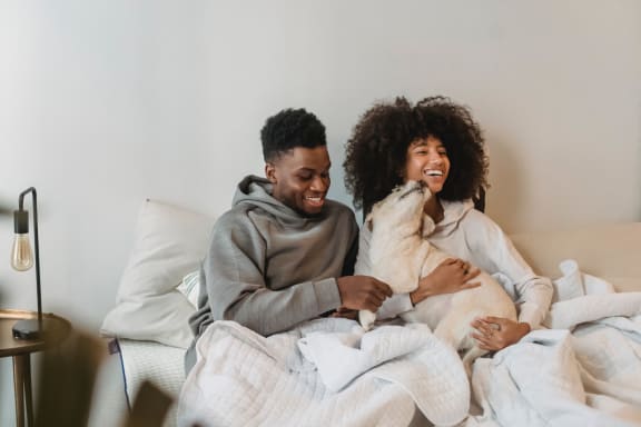 a man and woman sitting in bed with a dog