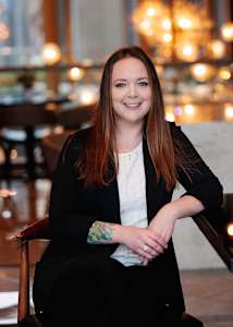 A woman with a tattoo on her left arm is sitting in a chair.
