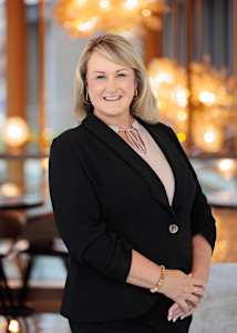 A woman in a black suit with a pink shirt underneath.