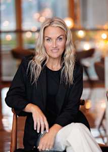 A woman with blonde hair is sitting in a chair.