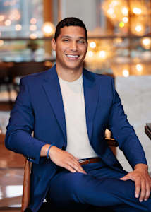 A man in a blue suit is sitting in a chair.