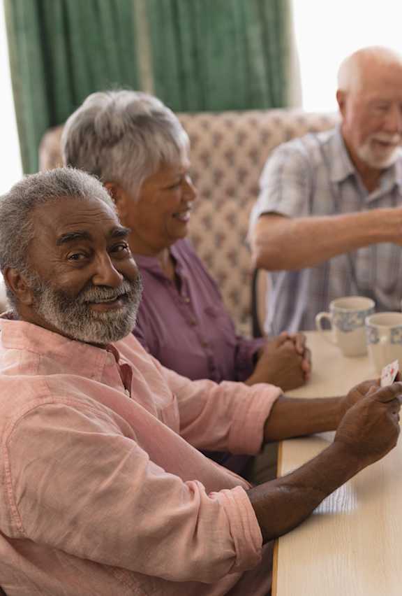 A group of elderly people are sitting around a table playing a card game.