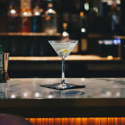 a martini glass on a bar with a lemon wedge in it