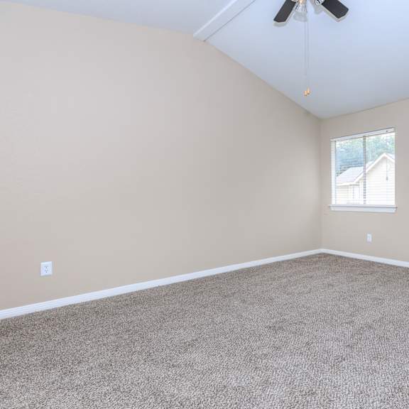A room with a carpeted floor and a ceiling fan.