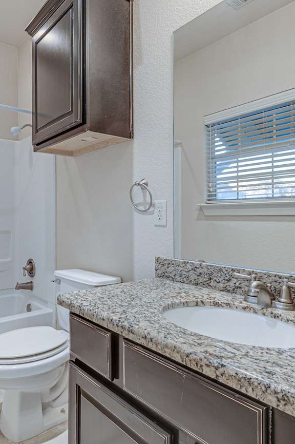 A bathroom with a white toilet and a sink. at Logan Ridge Apartments, Apartments, San Marcos, TX