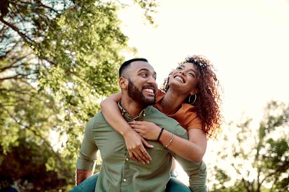 A man is carrying a woman on his back in a park.at Creekridge on the Park, Charlotte North Carolina